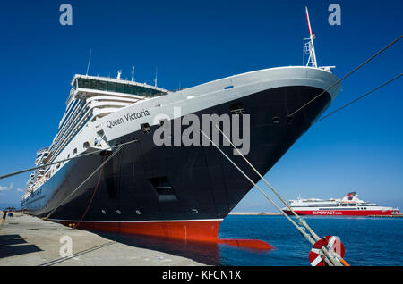 Hafen von Rhodos, Rhodos. Kreta. Griechenland. Der cunard Luxusliner, Königin Victoria, festgemacht am Kai. Es ist ein Sonniger Tag mit einer reinen blauen Himmel im Meer widerspiegelt. Stockfoto