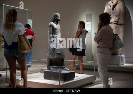 Turin. Italien. Besucher im Museo Egizio (Ägyptisches Museum) auf der Suche nach Exponaten. Bild, ägyptische Statue von Aanen, Zweiter Priester Amon. Neuer König Stockfoto