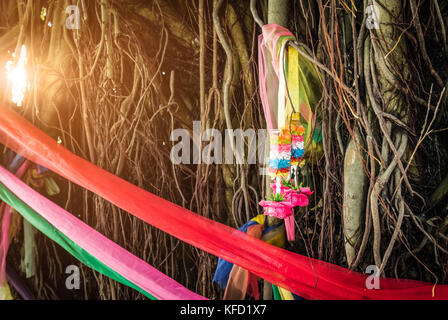 Fünf Farben Stoff umwickeln den Baum und Girlande auf Atemwurzel des banyan Baum mit Fackel Licht. Der Glaube der Thailänder. Möglichkeiten zum Schutz von Th Stockfoto