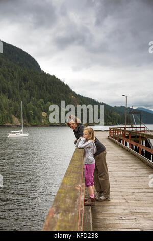 Kanada, Vancouver, British Columbia, Vater und Tochter Lean auf einem Geländer auf eine Dock auf gambier Island, in der Howe Sound Stockfoto