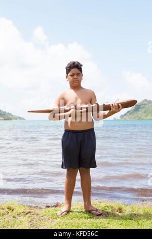 Französisch Polynesien Tahaa Island. Chris, ein kleiner Junge mit einem Holz- Kanu von seinem Vater. Sein Vater ist eine Skulptur und verkauft seine Stücke von THEI Stockfoto