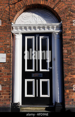 Verzierte weiße Türeinfassung mit geriffelten Pilastern und schwarz-weißer Viertäfeltür aus Holz St marys Place in Bury lancashire uk Stockfoto