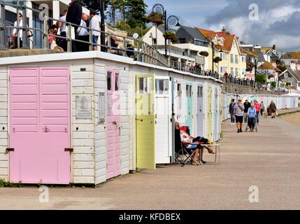 Menschen zu Fuß am Strand Hütten auf der Promenade in Lyme Regis, Dorset England UK Stockfoto