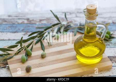 Olivenöl in Glas und Oliven auf Schneidebrett Stockfoto