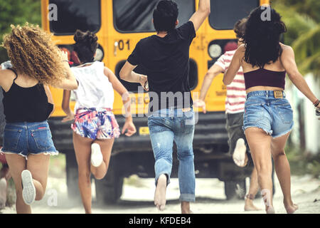 Eine Gruppe junger Leute jagen einem Moving School Bus. Stockfoto