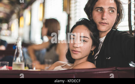 Junge Mann und die Frau in ein Stand in einem Diner nahe beieinander sitzen, entspannt, eine Frau im Hintergrund. Stockfoto