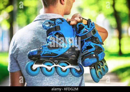 Junge männliche roller Skater holding Inline Skates. Von hinten Schießen. Stockfoto