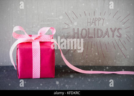 Grau grungy Betonwand mit englischen Kalligraphie frohe Feiertage. rosa Geschenk oder mit Bogen und Schneeflocken. Stockfoto