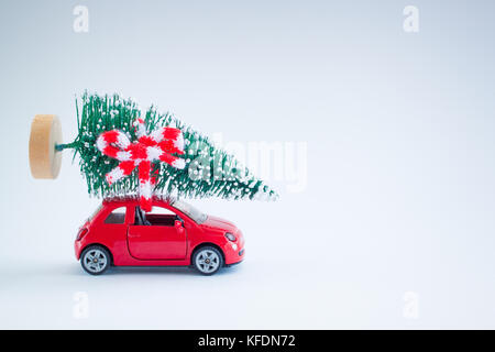 Die kleinen roten Auto mit Weihnachtsbaum auf der Oberseite aus Gewirken weißen und roten Schal. Mit einer Kopie - Raum. Stockfoto