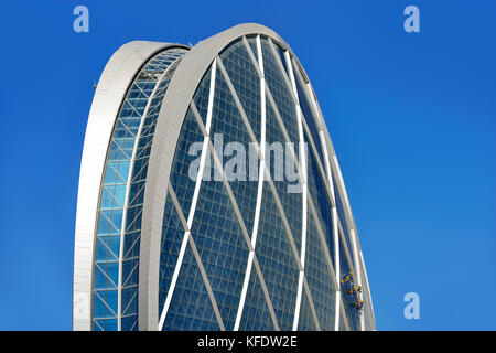 Fensterputzer hängen an der "Münze" Gebäude, Sitz der Aldar, einer der größten Immobiliengesellschaften in der Arabischen Stockfoto