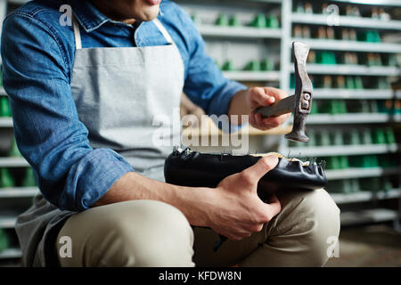 Professionelle Schuster hämmern Nägel in unfertigen Schuh in seiner Werkstatt Stockfoto