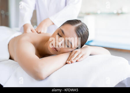 Eine ruhige Frau, die im Spa-Salon liegt und sich den Rücken massieren lässt Stockfoto
