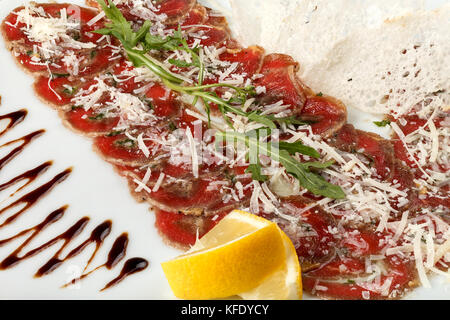 Carpaccio vom Rind mit Ruccola und Zitrone, Parmesan und Sauce. close-up Stockfoto