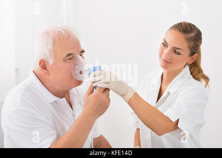 Ärztin suchen an der älteren männlichen Patienten inhalieren durch Sauerstoff Maske Stockfoto