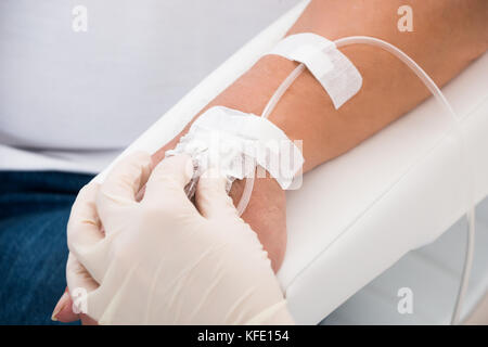 In der Nähe des Doctor's Hand mit Infusion in der Hand des Patienten eingefügt Stockfoto