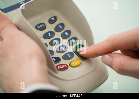 In der Nähe von Frau Hand Druck auf den Knopf an der Kreditkarte Maschine Stockfoto