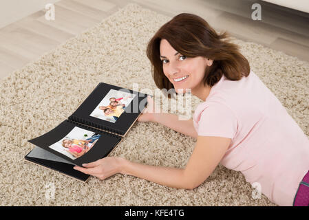 Liegende Frau auf dem Teppich mit Familie Fotoalbum Stockfoto