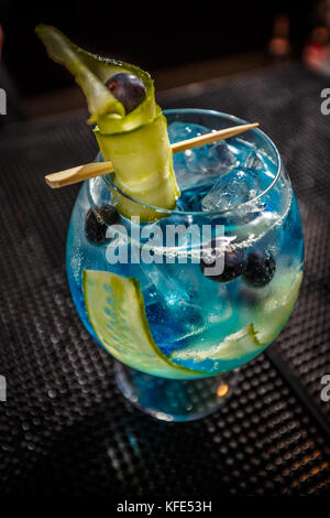 Blue Gin Tonic mit Gurke auf der Theke serviert. Stockfoto