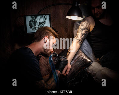 Professionelle Tätowierer macht ein Tattoo auf die Hand eines jungen Mannes Stockfoto