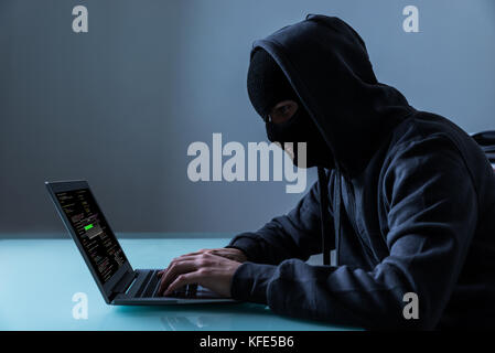 Hacker stehlen Daten von Laptop im Büro bei Nacht Stockfoto