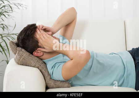 Menschen leiden unter Kopfschmerzen liegen auf Sofa Stockfoto