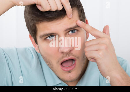 Schockiert, junger Mann auf Pickel auf der Stirn Stockfoto