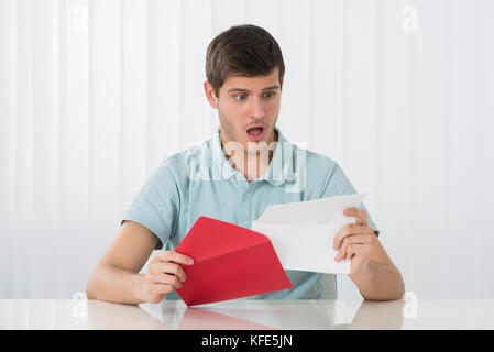 Portrait von Überrascht junger Mann auf der Suche nach Buchstaben Stockfoto