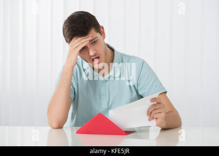 Portrait von Überrascht junger Mann auf der Suche nach Buchstaben Stockfoto
