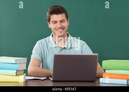 Junger Mann mit Laptop während des Studiums im Klassenzimmer Stockfoto