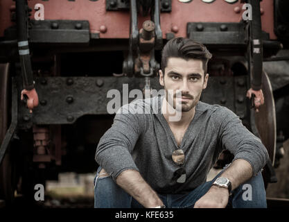 Hübscher junger Mann vor der alten Zug sitzen Stockfoto