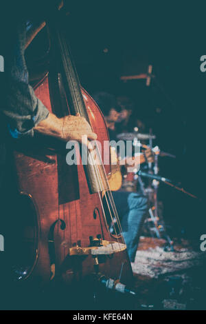 Vintage look Foto eines akustischen Trio Band auf einer Bühne in einem Nachtclub, mit der Double Bass Player im Fokus Stockfoto