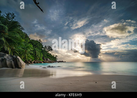 Sonnenstrahlen bei Sonnenuntergang hinter einer großen Wolke im Anse Georgette auf Praslin auf den Seychellen Stockfoto