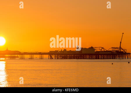 Palace Pier, Brighton im Morgengrauen. die Sonne die Szene in einem sanften orange Glühen gebadet hat Stockfoto