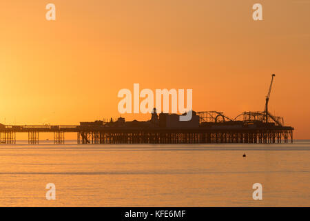 Palace Pier, Brighton im Morgengrauen. die Sonne die Szene in einem sanften orange Glühen gebadet hat Stockfoto