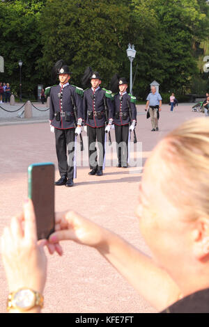 Eine Frau touristische nimmt Fotos als des Königs Guard für die Wachablösung im Königlichen Palast, Oslo, Norwegen vorzubereiten. Stockfoto