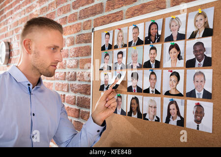 Unternehmer die Auswahl der Kandidaten Foto auf der Pinnwand im Büro angeschlossen Stockfoto