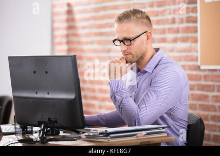 Ernsthafte junge Unternehmer tragen Brillen mit Computer im Büro Stockfoto