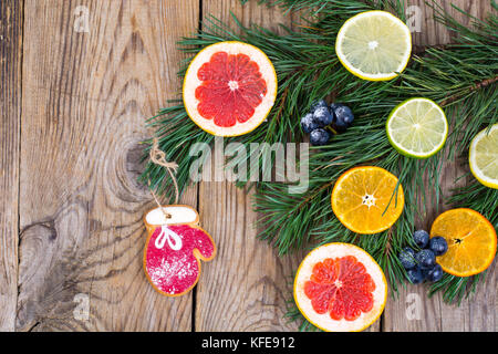 Hausgemachte Lebkuchen cookies verglast und Weihnachtsbaum Zweige mit Früchten. Stockfoto