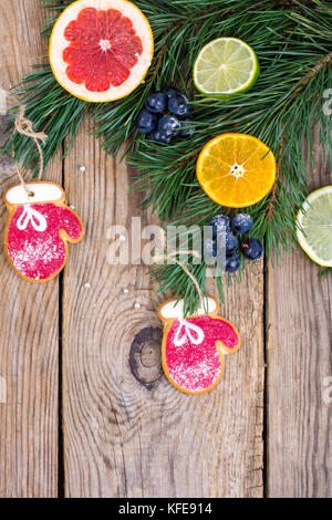 Hausgemachte Lebkuchen cookies verglast und Weihnachtsbaum Zweige mit Früchten. Stockfoto