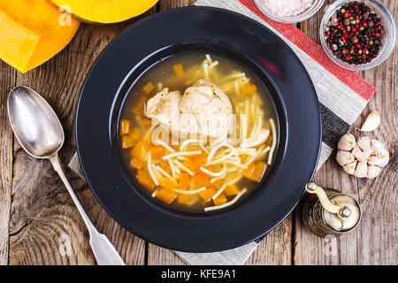 Suppe mit Hähnchen, Kürbis und Nudeln auf hölzernen Tisch Stockfoto
