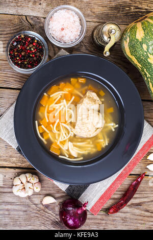 Suppe mit Hähnchen, Kürbis und Nudeln auf hölzernen Tisch Stockfoto