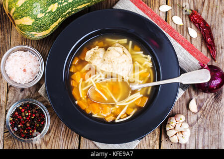Suppe mit Hähnchen, Kürbis und Nudeln auf hölzernen Tisch Stockfoto