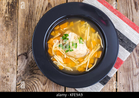 Suppe mit Hähnchen, Kürbis und Nudeln auf hölzernen Tisch Stockfoto