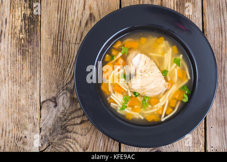 Suppe mit Hähnchen, Kürbis und Nudeln auf hölzernen Tisch Stockfoto