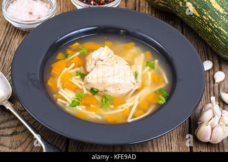 Suppe mit Hähnchen, Kürbis und Nudeln auf hölzernen Tisch Stockfoto