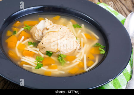 Suppe mit Hähnchen, Kürbis und Nudeln auf hölzernen Tisch Stockfoto