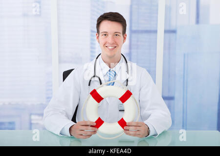 Portrait von selbstbewussten jungen männlichen Arzt holding Rettungsring in der Klinik Stockfoto