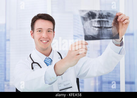 Lächelnden jungen männlichen Arzt Prüfung zahnmedizinische Röntgensysteme im Krankenhaus Stockfoto
