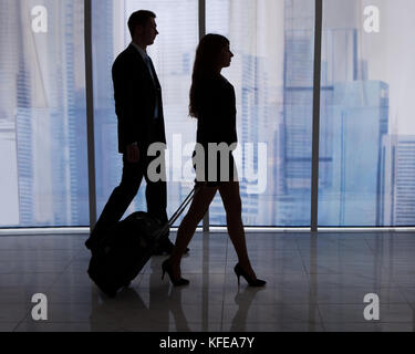 Die ganze Länge der junge Geschäftsmann und Geschäftsfrau wandern mit Gepäck in Office Stockfoto