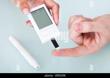 Zugeschnittenes Bild der Arzt prüfen Blutzuckerspiegel von männlichen Patienten in der Klinik Stockfoto